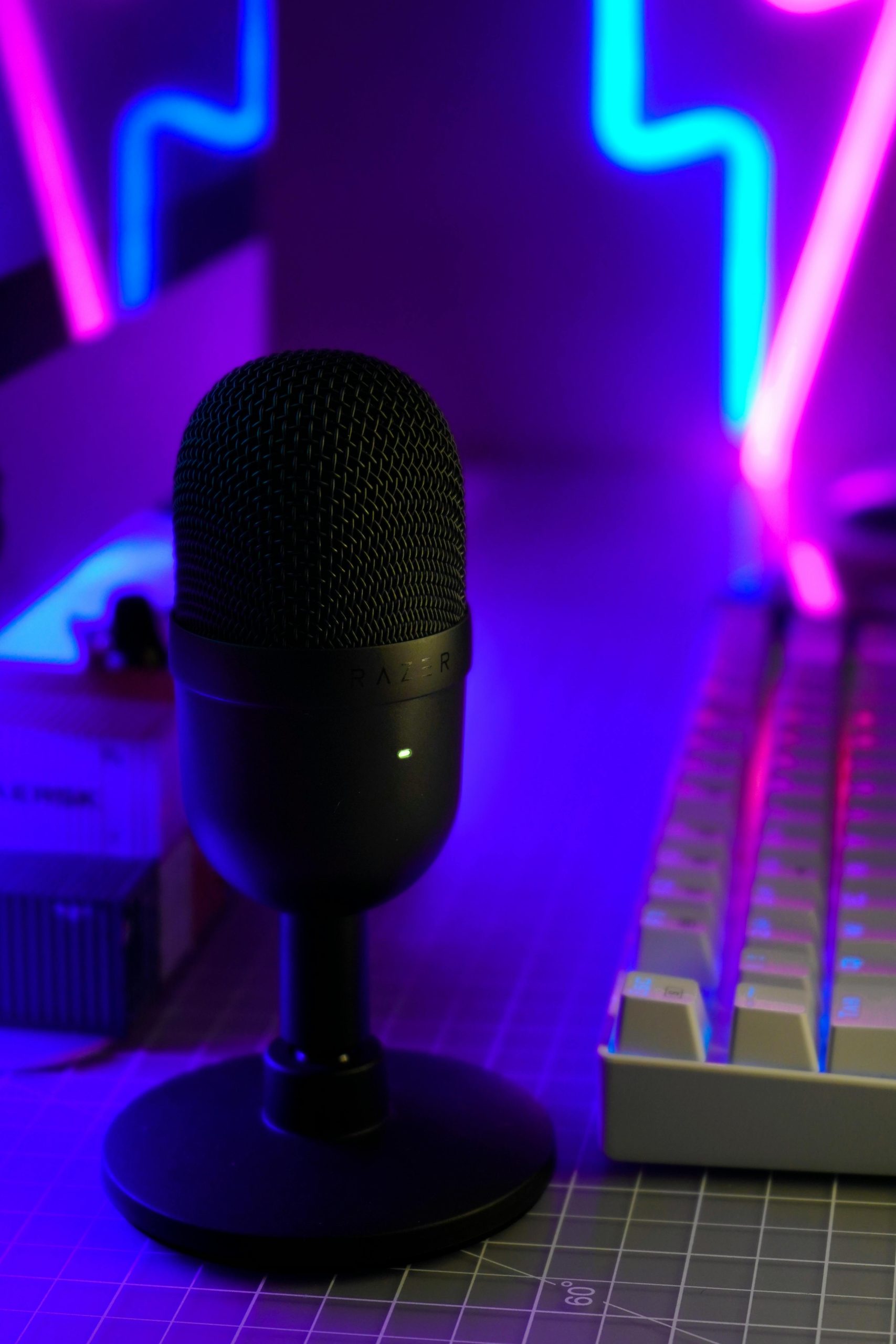 Close-up of a condenser microphone and keyboard in a neon-lit modern workspace. Perfect for creative studios.